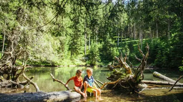 Kinder halten ihre Füße ins kalte Wasser eines kleinen Sees